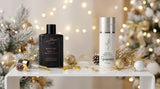 Vera Moore skincare duo featured in a festive holiday product photoshoot on a white acrylic table. On the left, the dark "RESTORE Beauty Oil" with its gold and glass dropper and golden oil drops. On the right, the white "Lift & Firm Peptide Serum" with its silver cap. The table is elegantly styled with gold and white holiday decorations, including sparkly ornaments, frosted pinecones, and evergreen sprigs, with a warm, blurry background of golden holiday fairy lights and a Christmas tree.